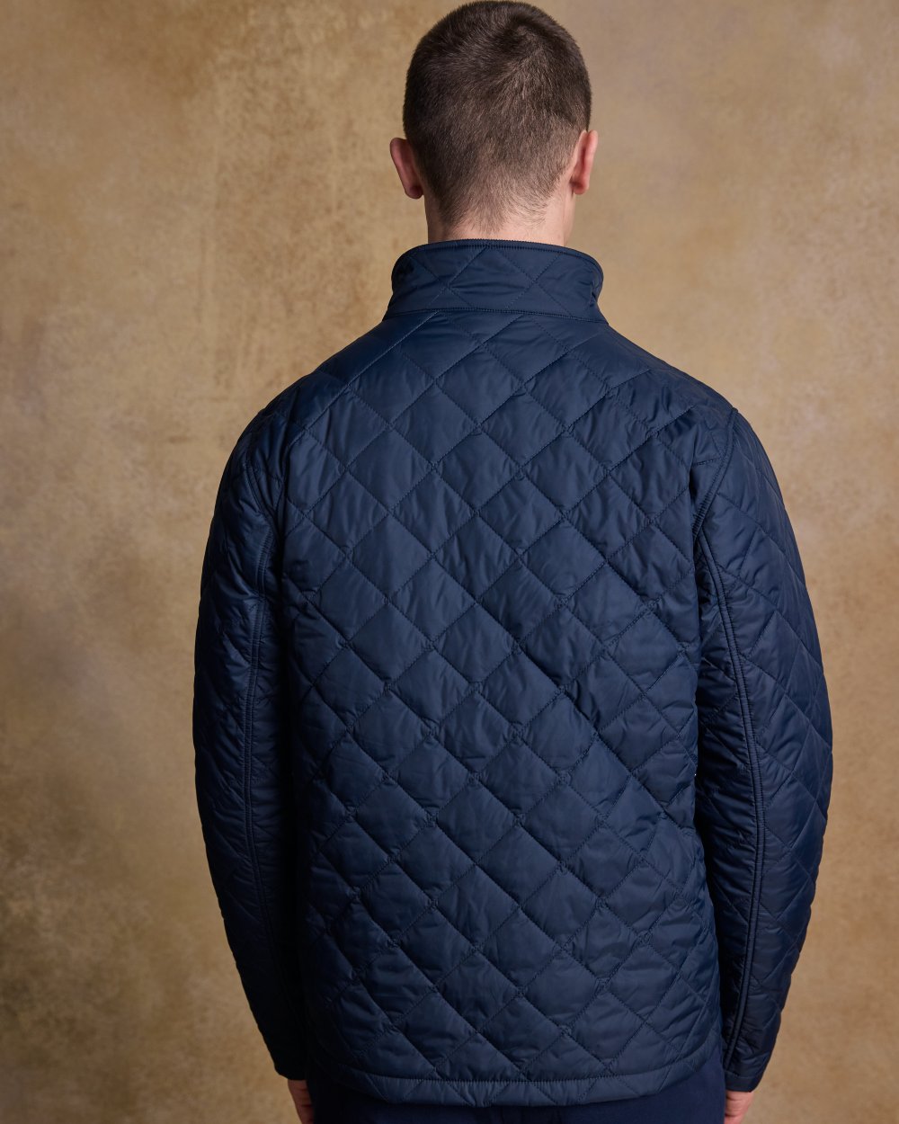 Navy coloured Jack Murphy Ronan Quilted Jacket on wall background 