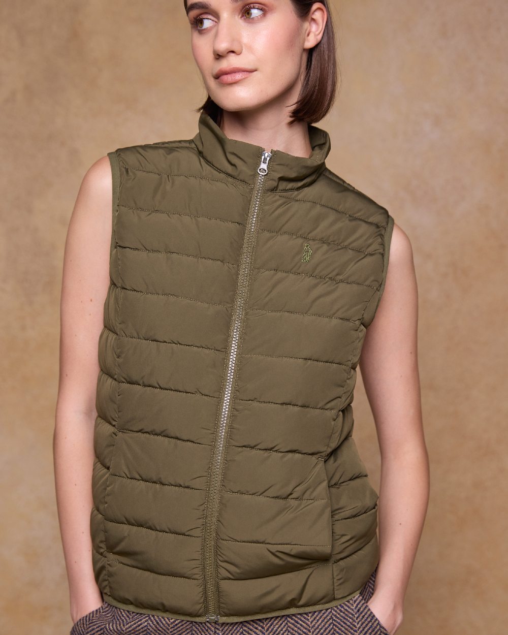 Olive Coloured Jack Murphy Womens Leah Puffa Gilet on indoor background 