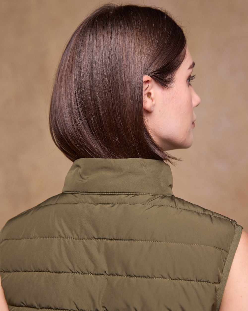 Olive Coloured Jack Murphy Womens Leah Puffa Gilet on indoor background 