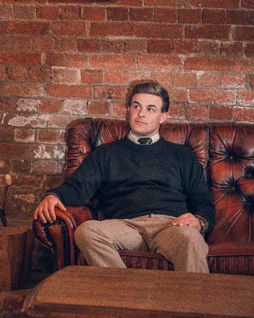 Dark Olive coloured Jack Pyke Ashcombe Lambswool Crewknit Pullover on brick wall background 