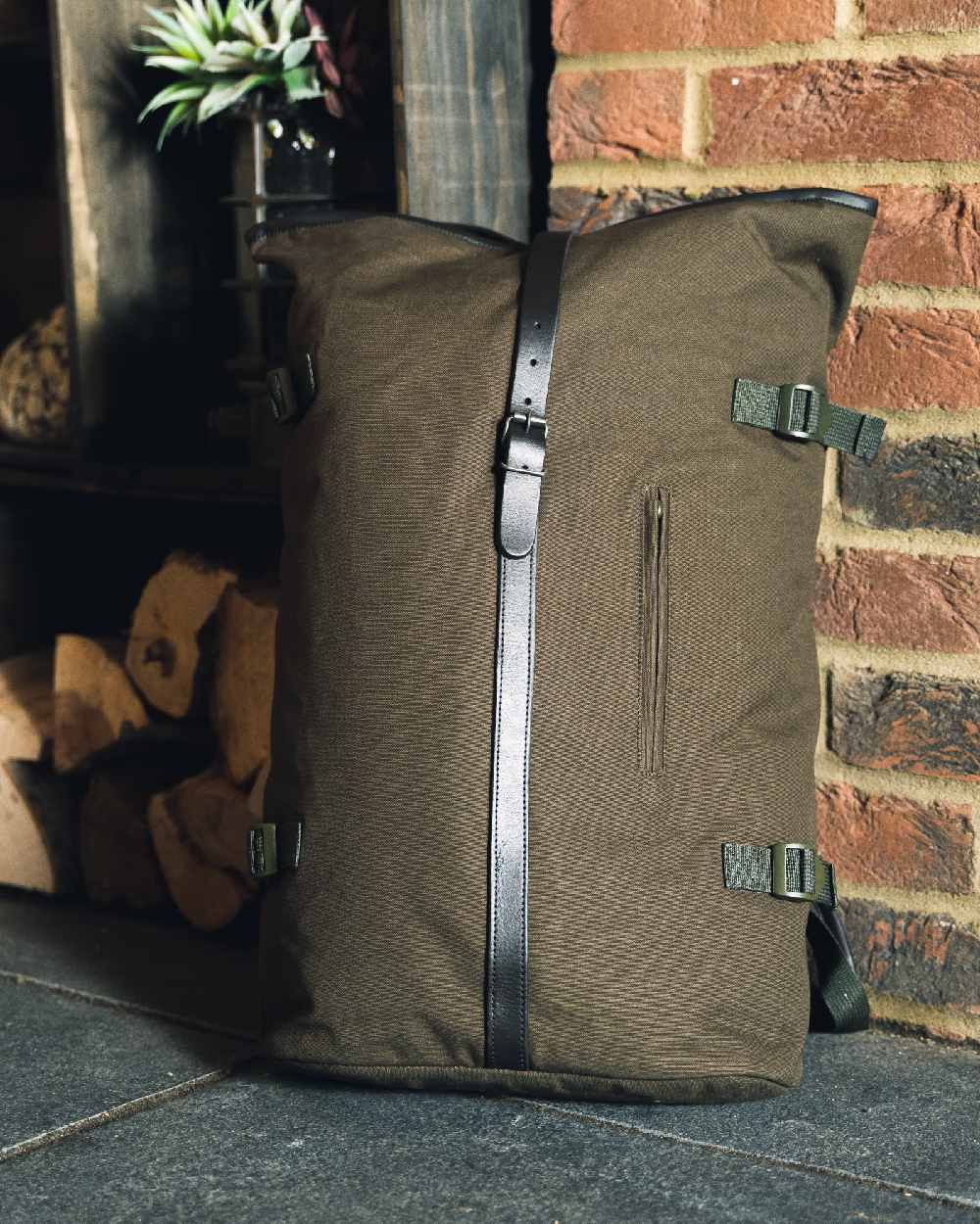 Green coloured Jack Pyke Canvas Fold Top Rucksack on brick wall background 