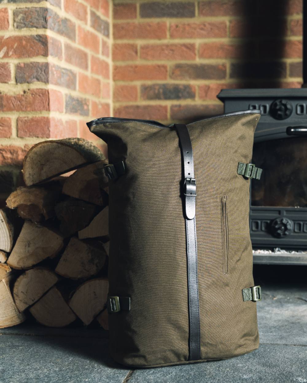 Green coloured Jack Pyke Canvas Fold Top Rucksack on brick wall background 