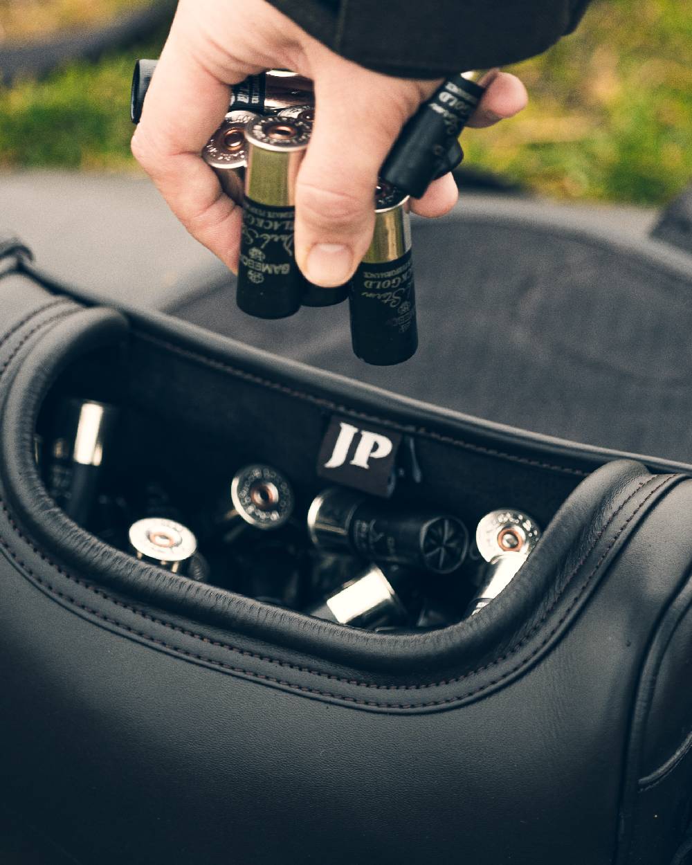 Brown coloured Jack Pyke Leather Cartridge Bag on blurry background 