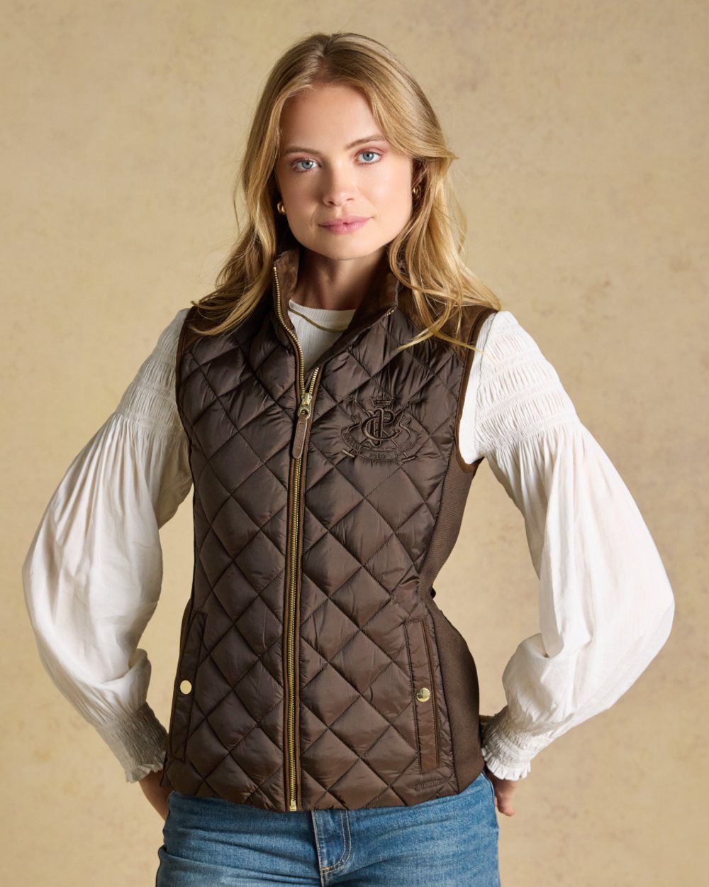 Chocolate Brown coloured Joules Braemar Luxe Gilet on tan background 