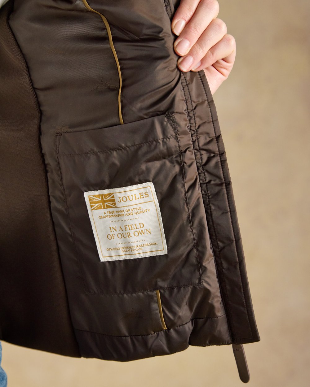 Chocolate Brown coloured Joules Braemar Luxe Gilet on tan background 