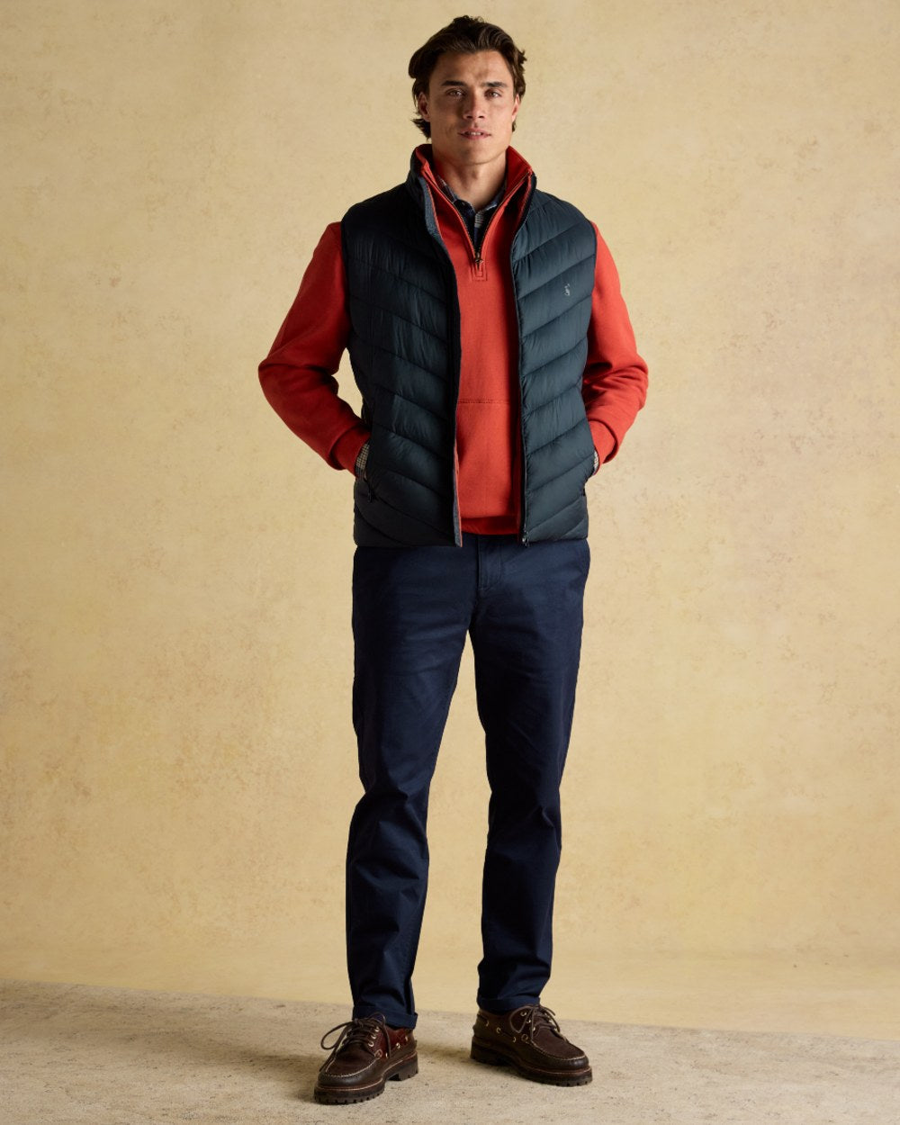 Navy coloured Joules Mens Garrett Showerproof Padded Gilet on wall background 