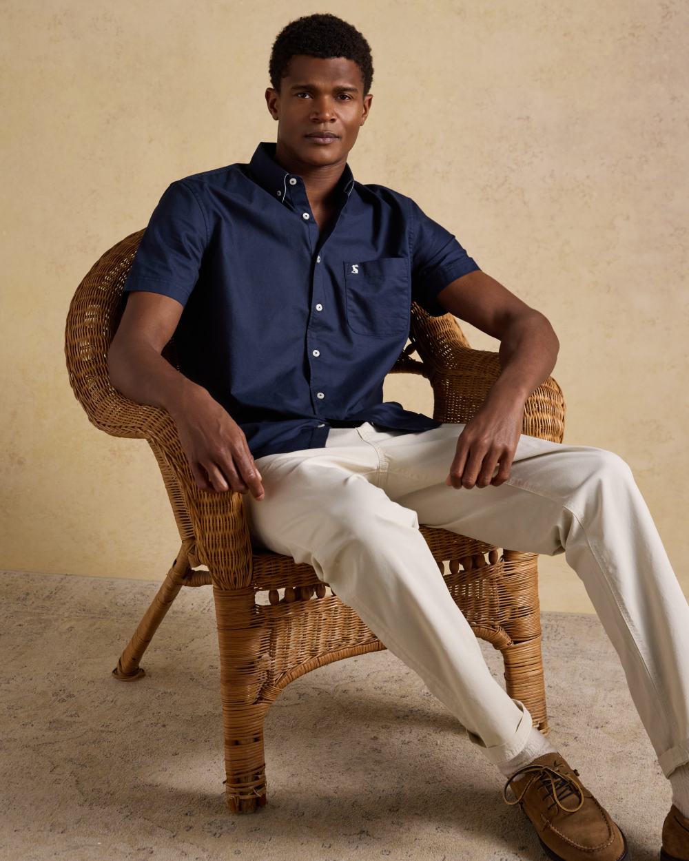 Navy coloured Joules Mens Oxford Short Sleeve Classic Fit Cotton Shirt on wall background 