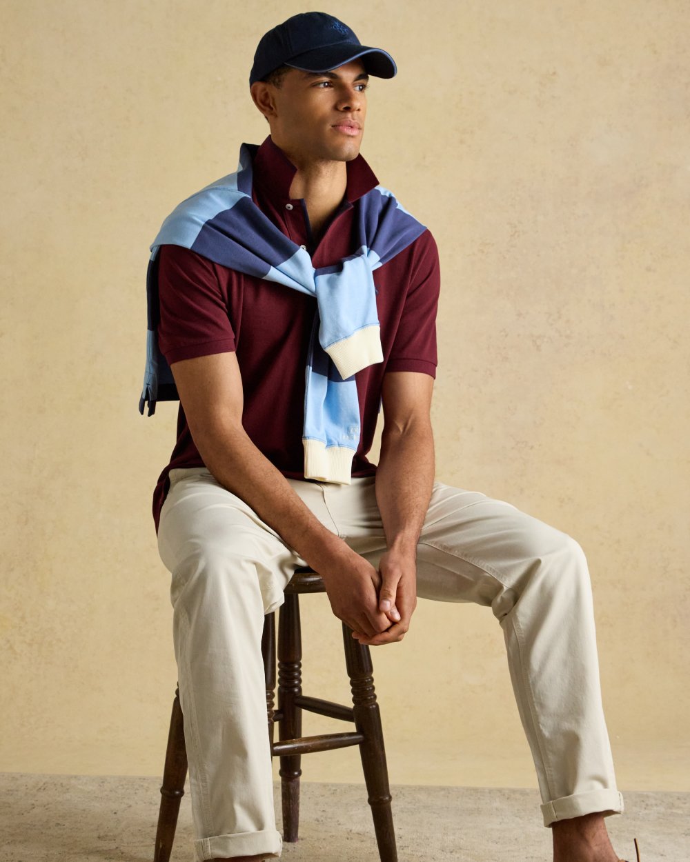 Burgundy coloured Joules Mens Woody Cotton Pique Polo Shirt on wall background 
