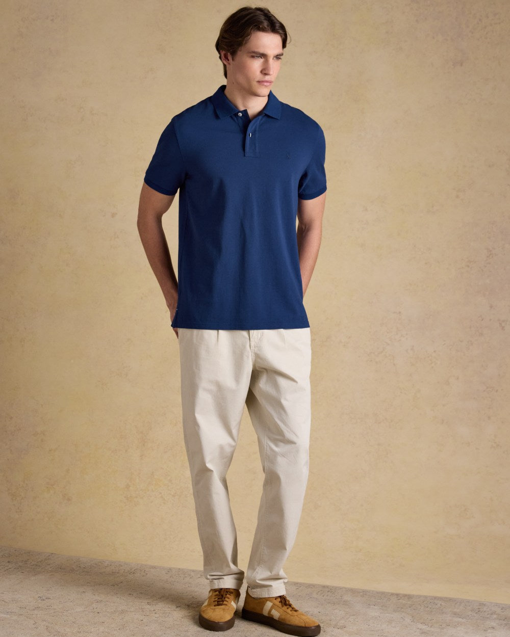 Dark Blue coloured Joules Mens Woody Cotton Pique Polo Shirt on wall background 