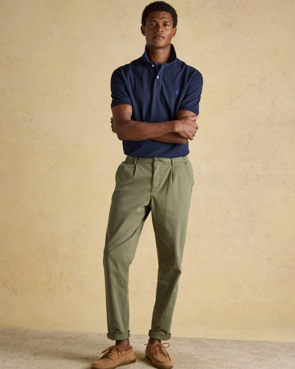 Navy coloured Joules Mens Woody Cotton Pique Polo Shirt on wall background 