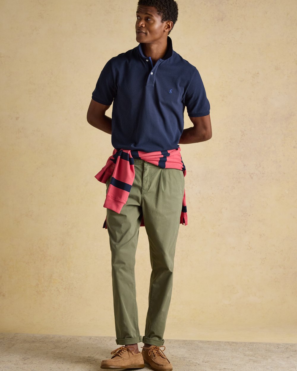 Navy coloured Joules Mens Woody Cotton Pique Polo Shirt on wall background 