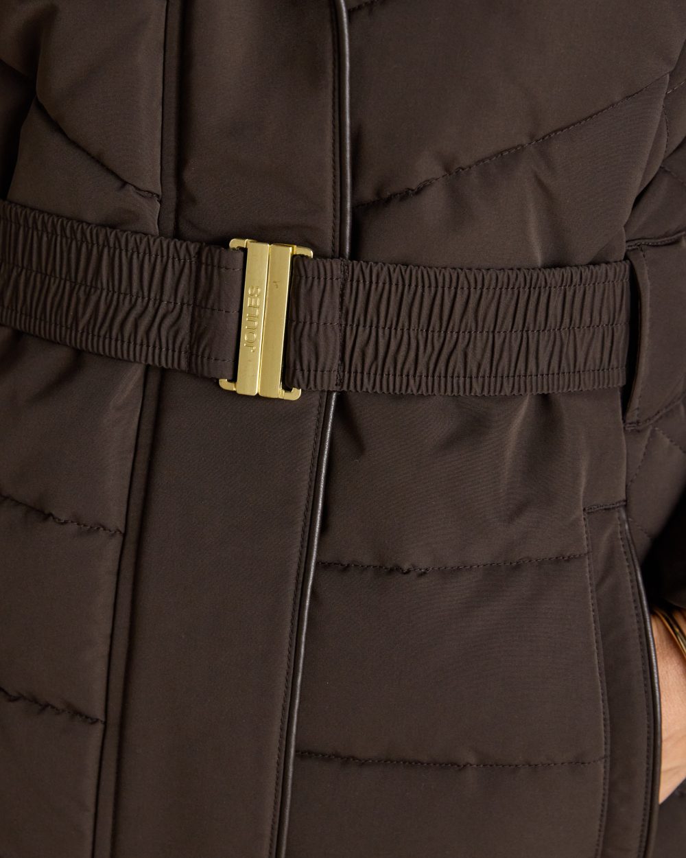 Brown Coloured Joules Womens Aspen Showerproof Padded Coat on wall background 