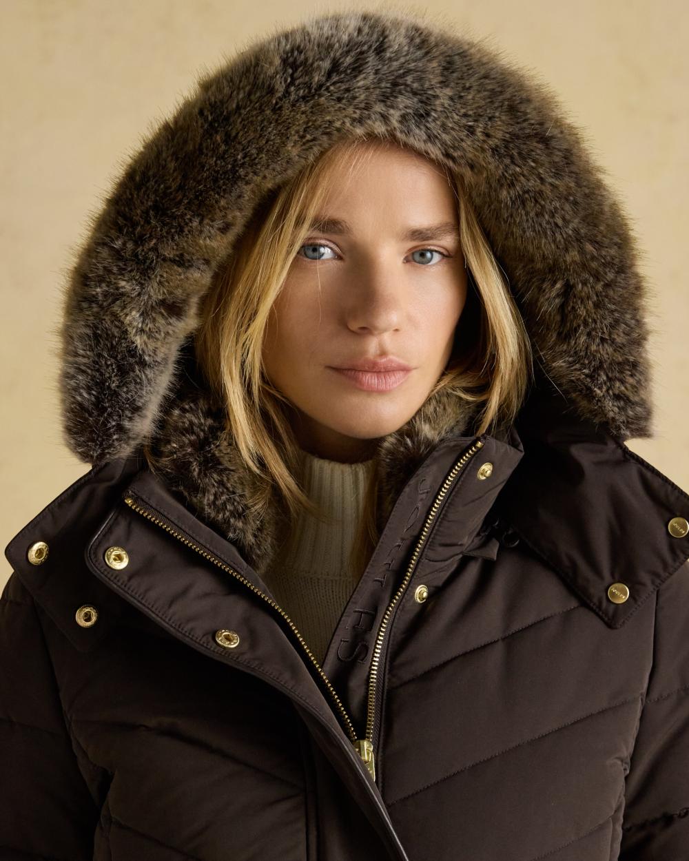 Brown Coloured Joules Womens Aspen Showerproof Padded Coat on wall background 