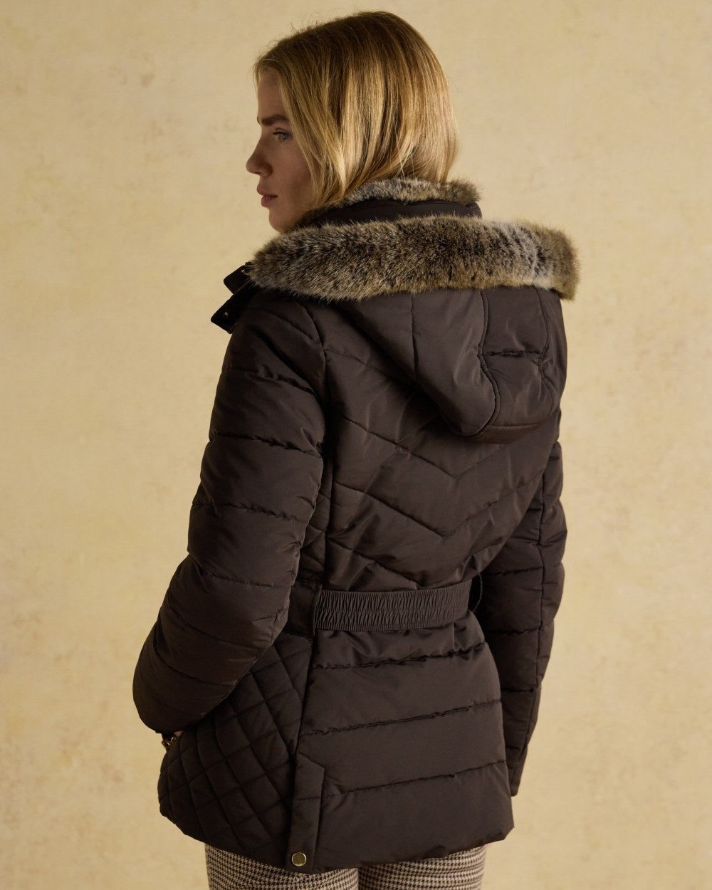 Brown Coloured Joules Womens Aspen Showerproof Padded Coat on wall background 