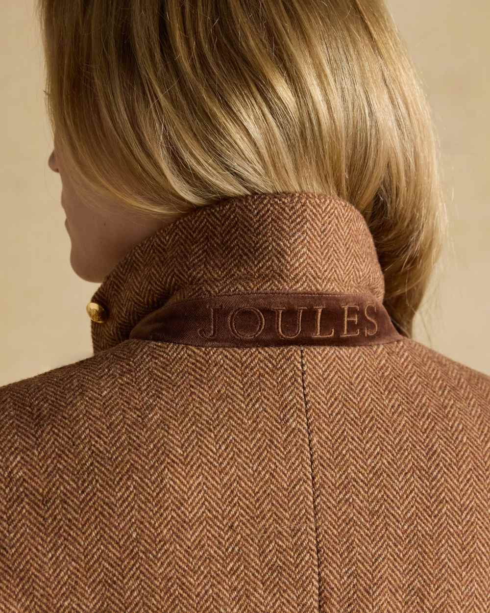 Brown Herringbone coloured Joules Womens Canterly Tweed Hacking Jacket on wall background 