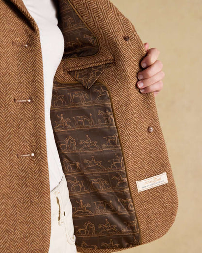 Brown Herringbone coloured Joules Womens Canterly Tweed Hacking Jacket on wall background 