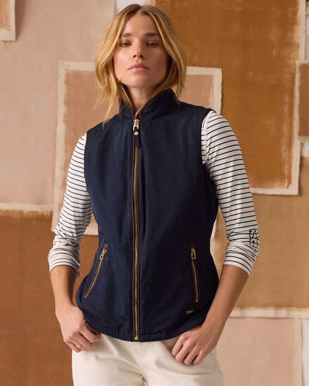 Navy coloured Joules Womens Farnham Fleece Lined Lightweight Gilet on wall background 