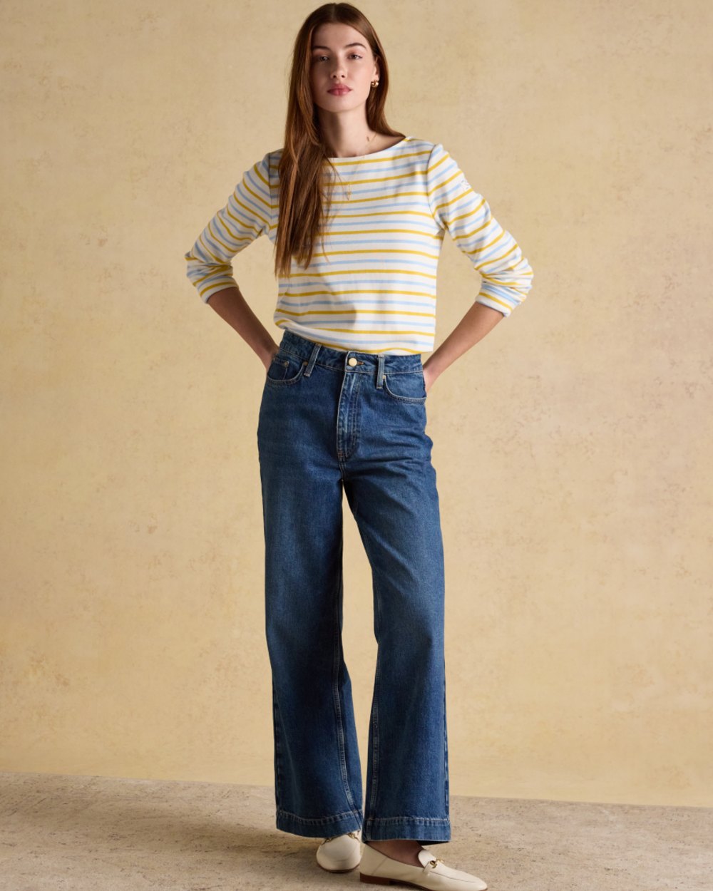 Blue yellow Stripe coloured Joules Womens Harbour Long Sleeve Striped Boat Neck Breton Top on wall background 