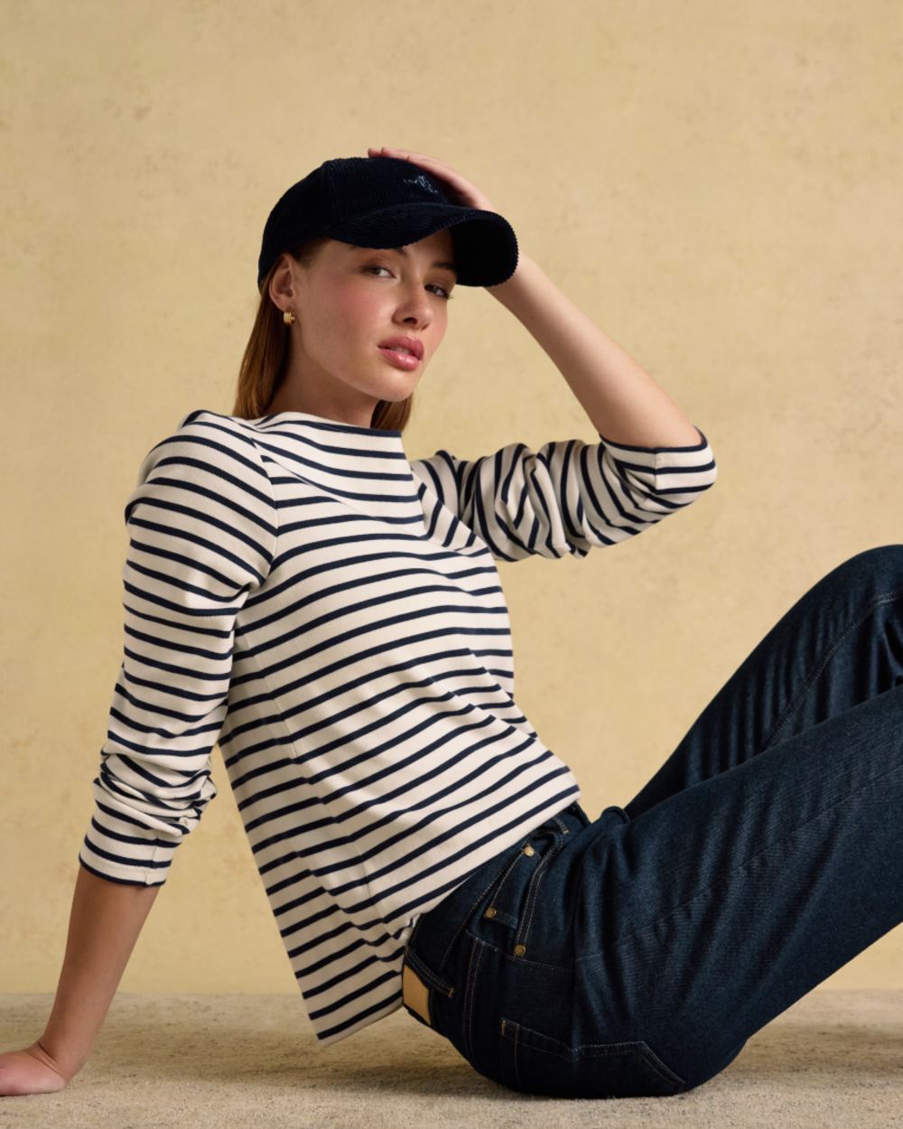 Cream Navy coloured Joules Womens Harbour Long Sleeve Striped Boat Neck Breton Top on wall background 