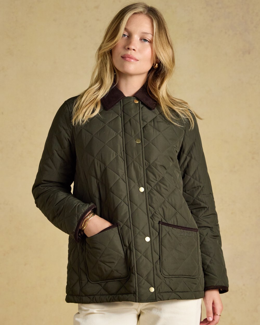 Khaki Green coloured Joules Womens Highgrove Diamond Quilted Jacket on beige background 