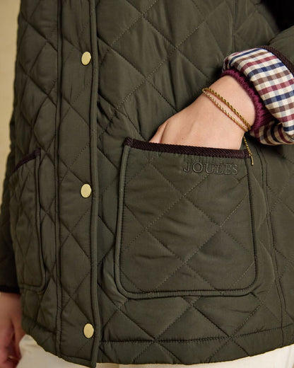 Khaki Green coloured Joules Womens Highgrove Diamond Quilted Jacket on beige background 
