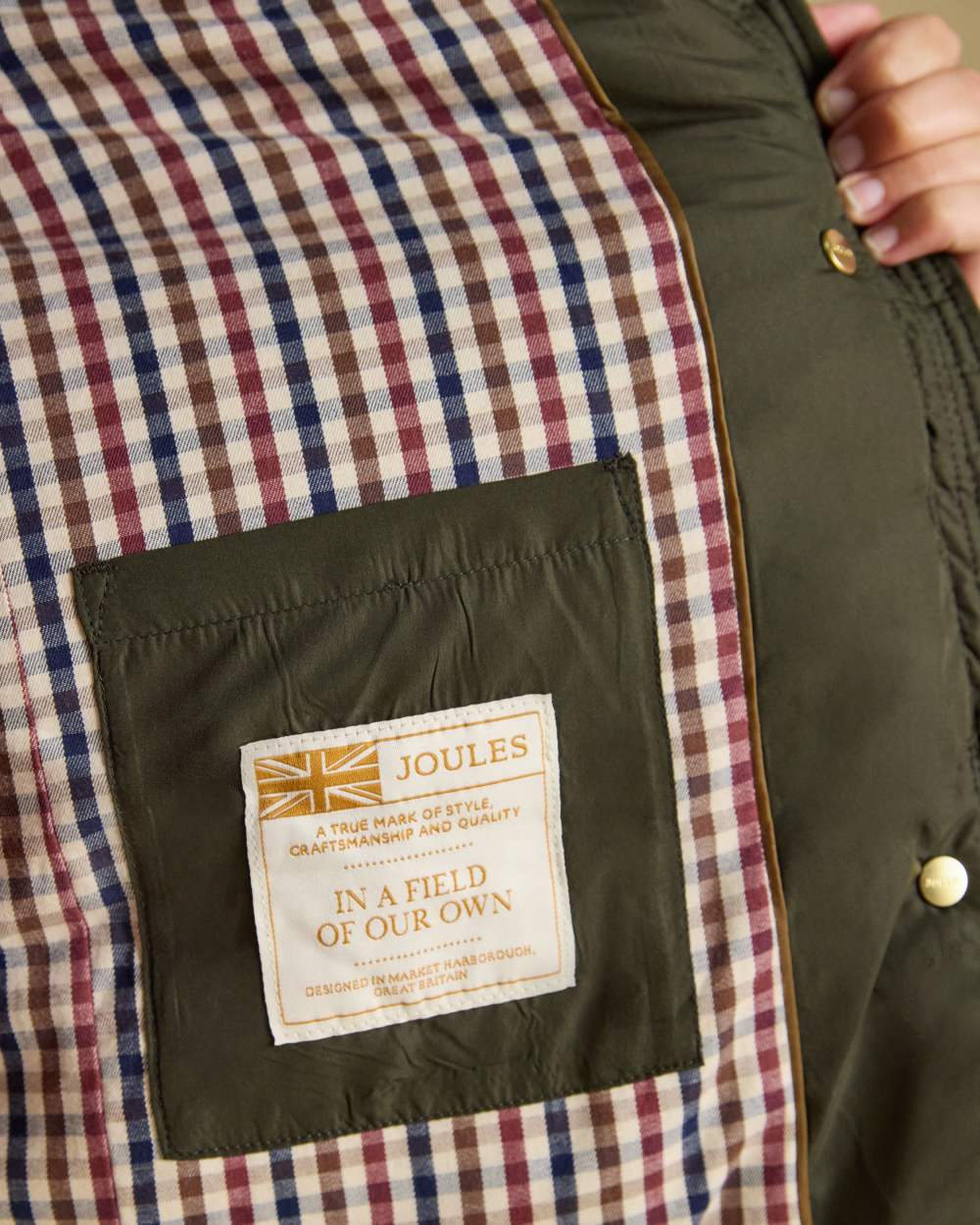 Khaki Green coloured Joules Womens Highgrove Diamond Quilted Jacket on beige background 