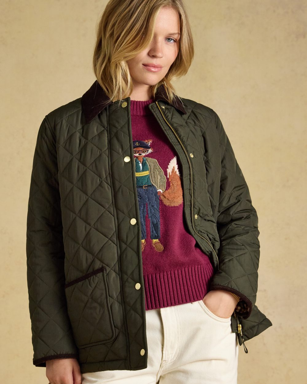 Khaki Green coloured Joules Womens Highgrove Diamond Quilted Jacket on beige background 