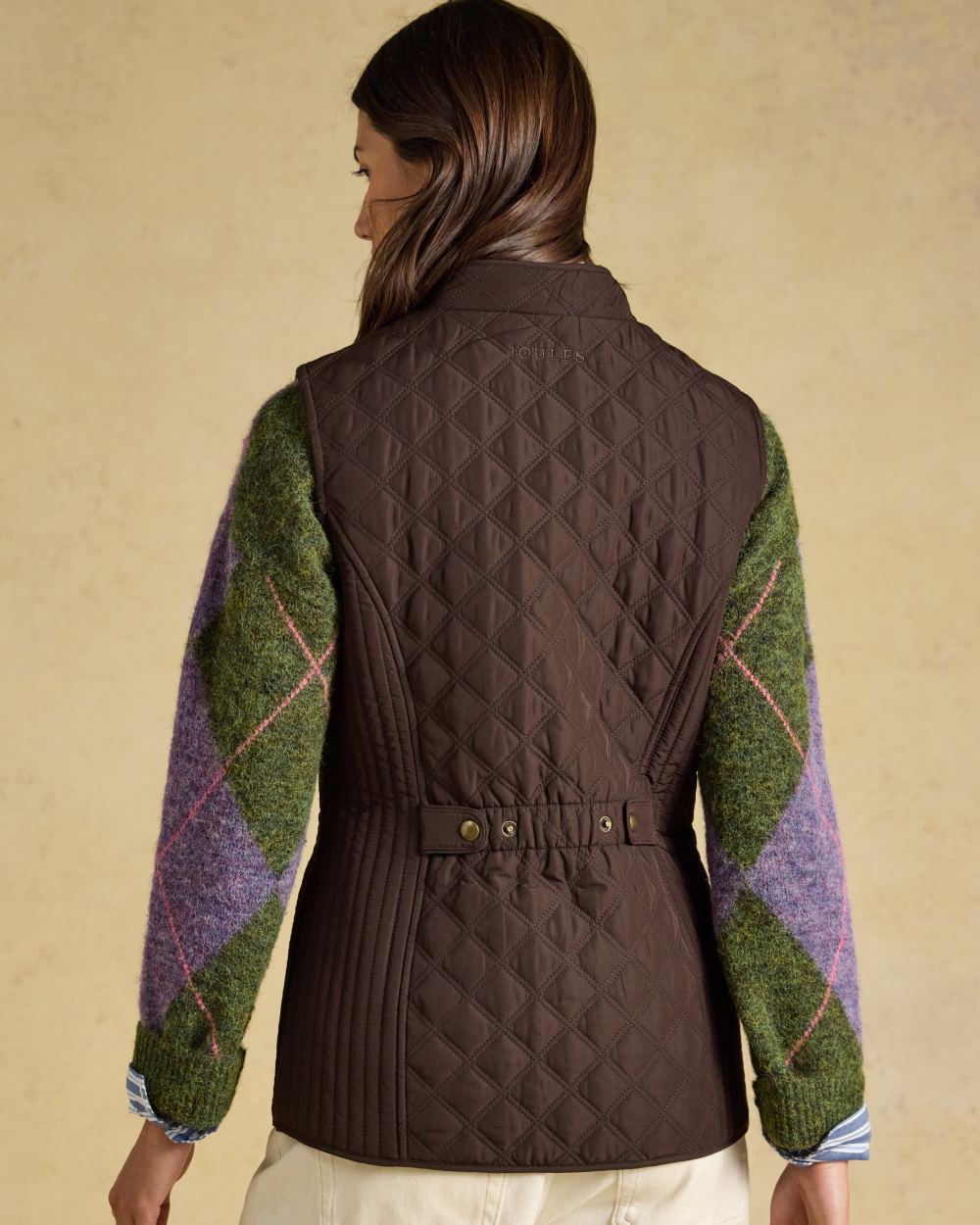 Chocolate Brown Coloured Joules Minx Showerproof Diamond Quilted Gilet on wall background 
