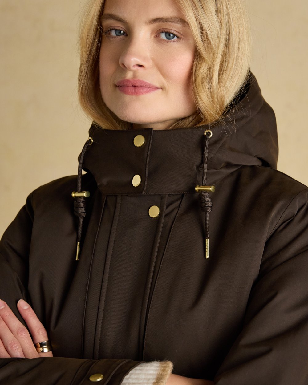 Chocolate Brown coloured Joules Womens Warmwell Waterproof Fleece Lined Raincoat on tan background 