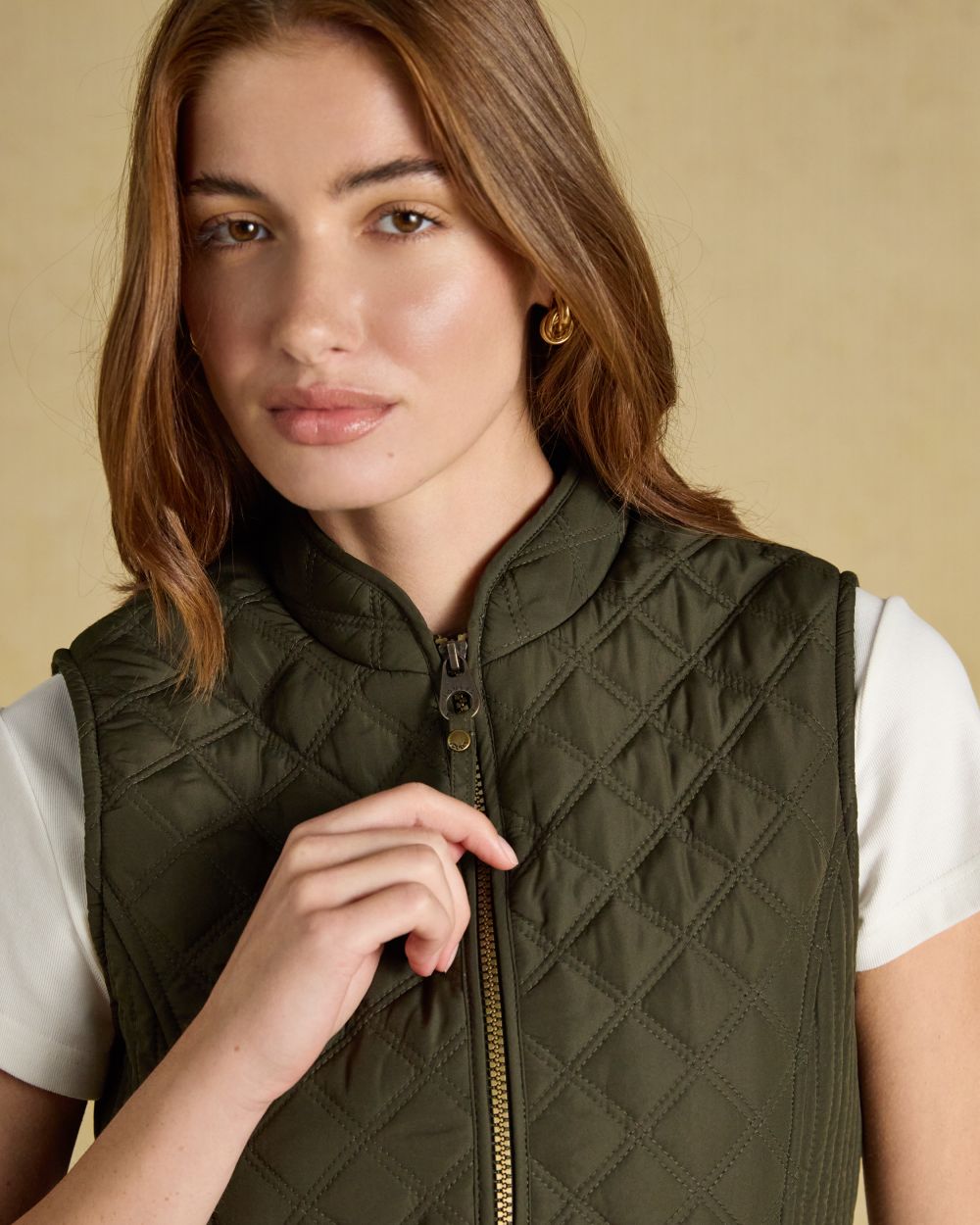 Green coloured Joules Womens Minx Showerproof Diamond Quilted Gilet on a gold background 