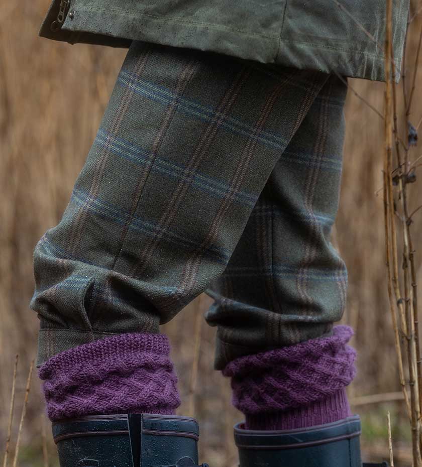Laksen Green tweed shooting breeks with lilac shooting socks with a reed background.