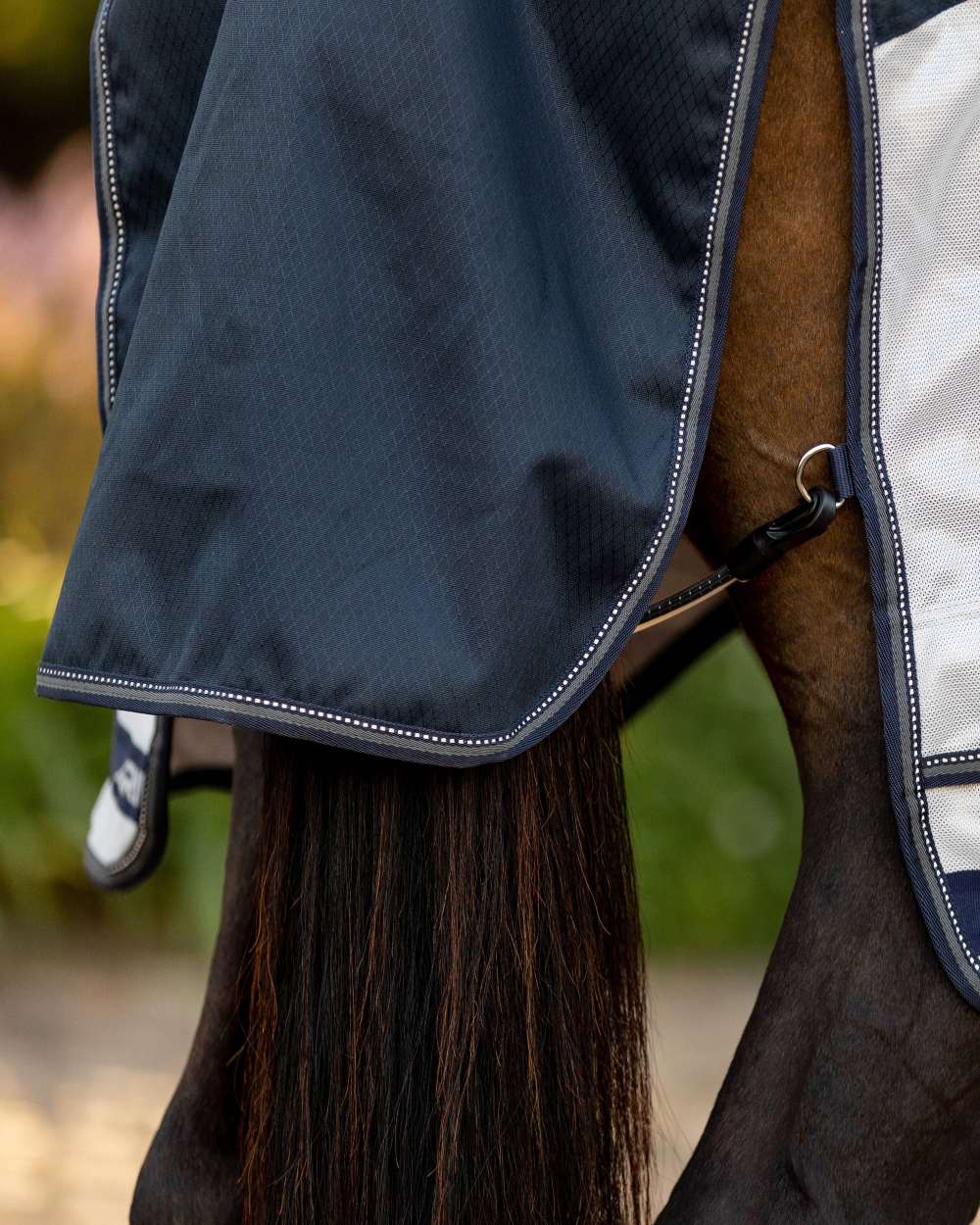 Navy coloured LeMieux Arika Shower Tek Fly Rug on blurry background 