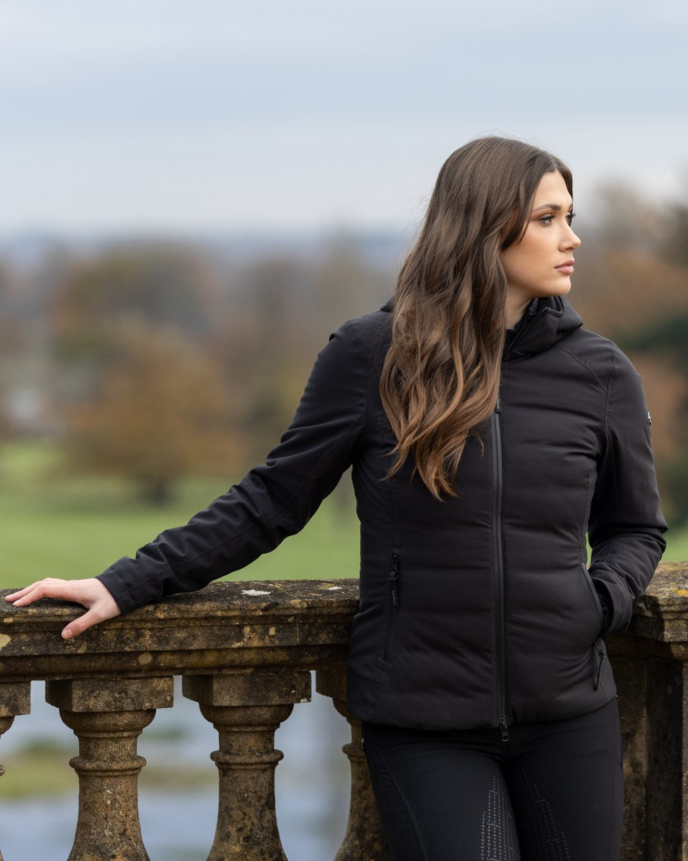 Black coloured LeMieux Brooke Waterproof Hybrid Jacket on fence background 