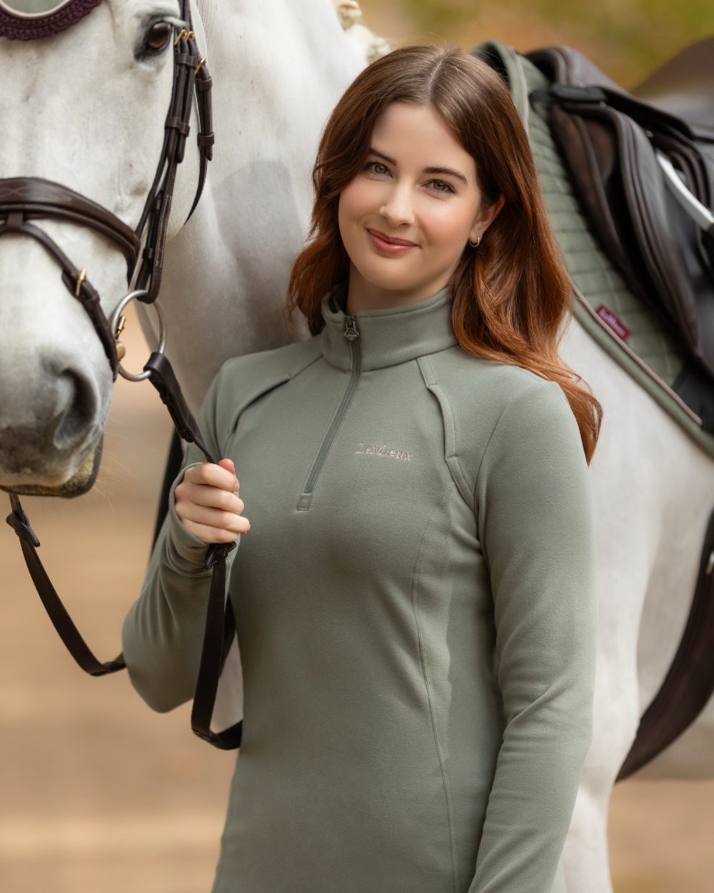 Rosemary coloured LeMieux Frances Quarter Zip Fleece on blurry background 