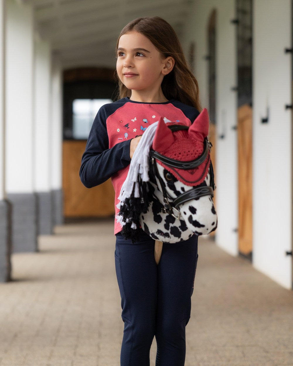 Cranberry coloured LeMieux Hobby Horse Fly Hood on outdoor background 