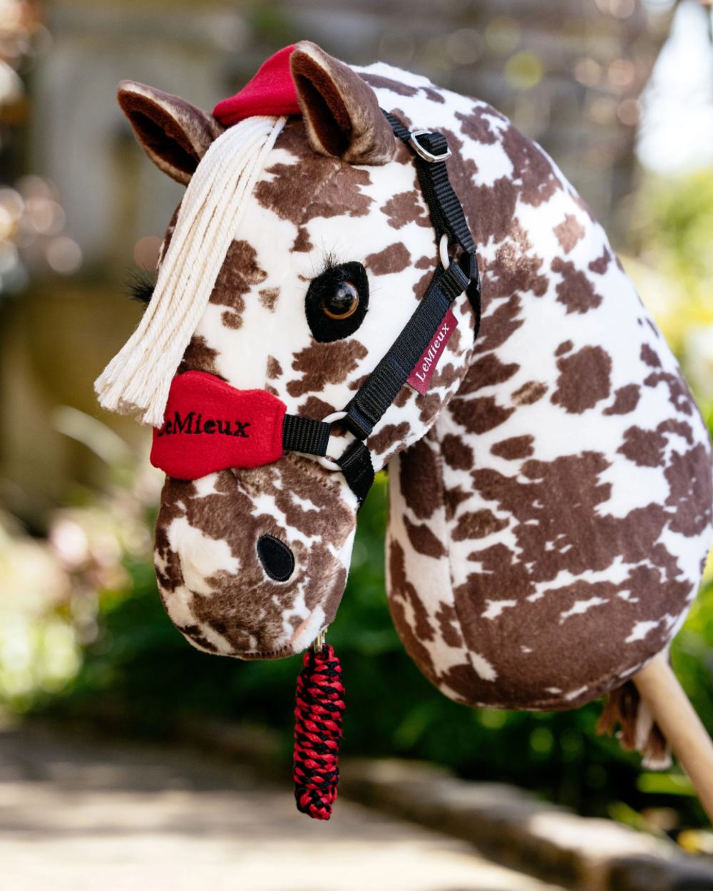 Chilli coloured LeMieux Hobby Horse Vogue Headcollar on backyard background 