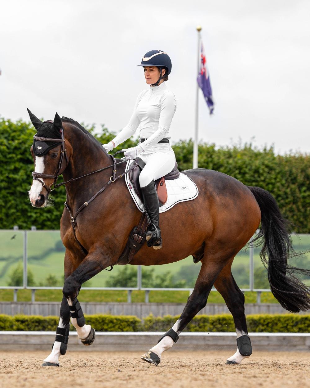 White coloured LeMieux Loire GP Square Pad on riding arena background 