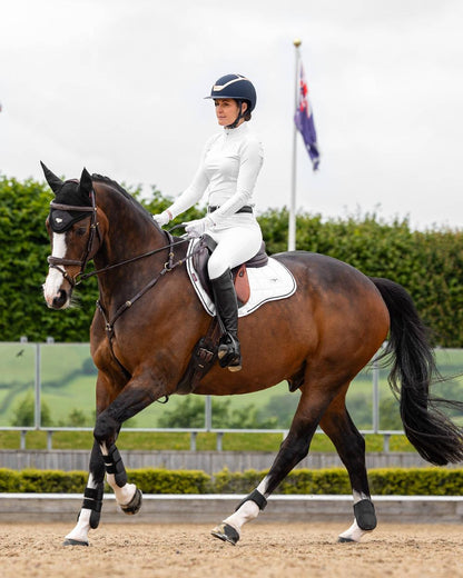 White coloured LeMieux Loire GP Square Pad on riding arena background 