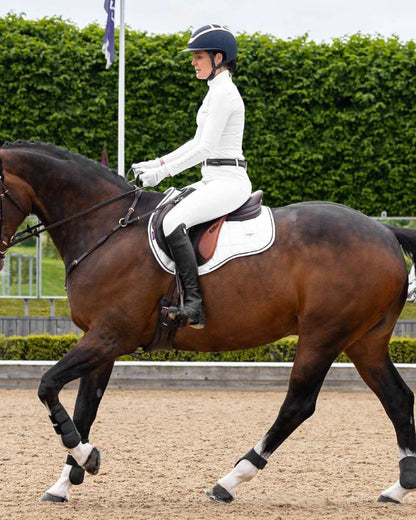 White coloured LeMieux Loire GP Square Pad on riding arena background 