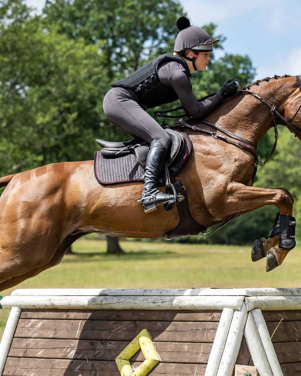 Cinder coloured LeMieux Suede Close Contact Squares on riding arena background 