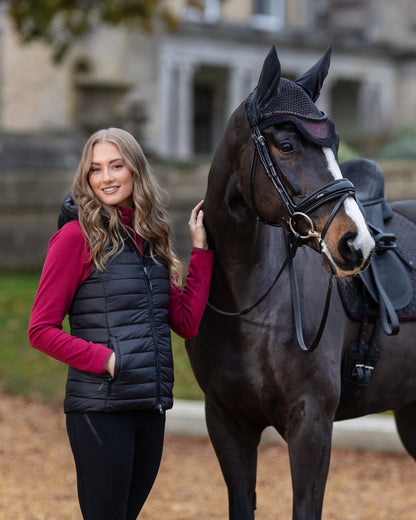 Black coloured LeMieux Tilly Hooded Puffer Gilet on blurry background 