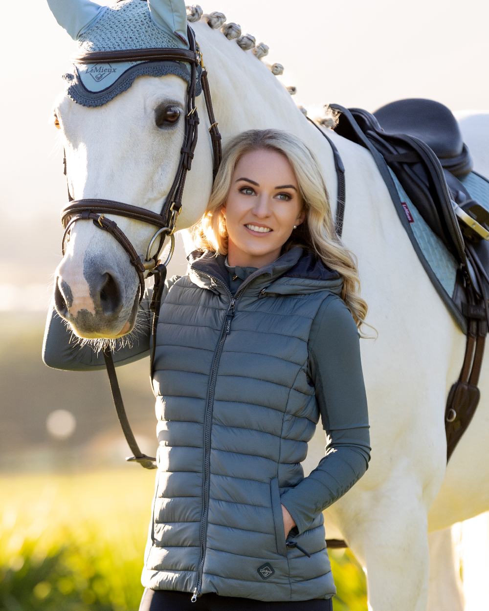 Petrol coloured LeMieux Tilly Hooded Puffer Gilet on blurry background 