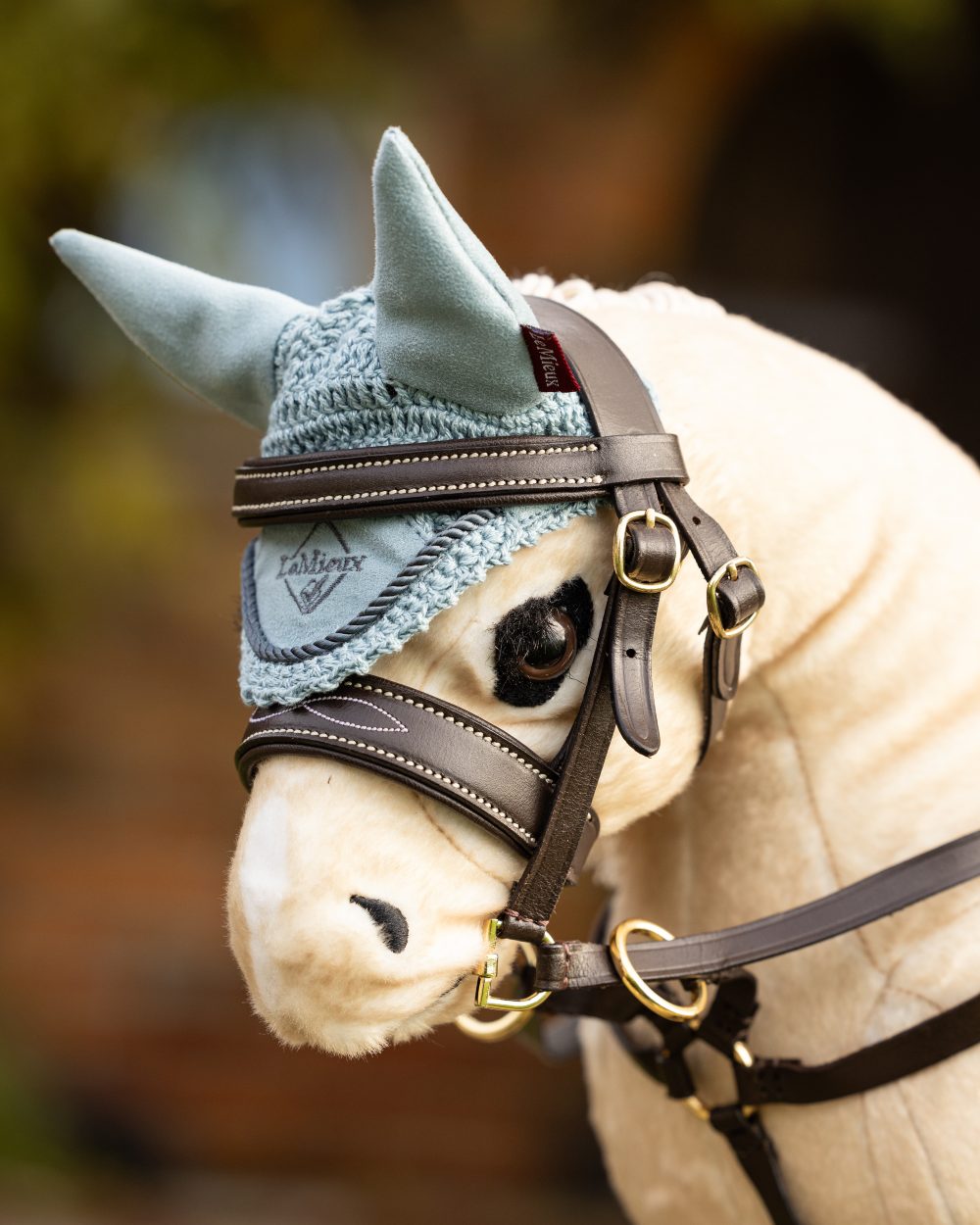 Glacier coloured LeMieux Toy Pony Fly Hood on blurry background 