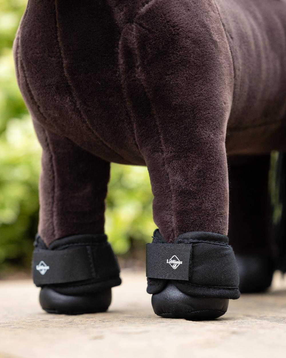 Black coloured LeMieux Toy Pony Over Reach Boots on blurry background 