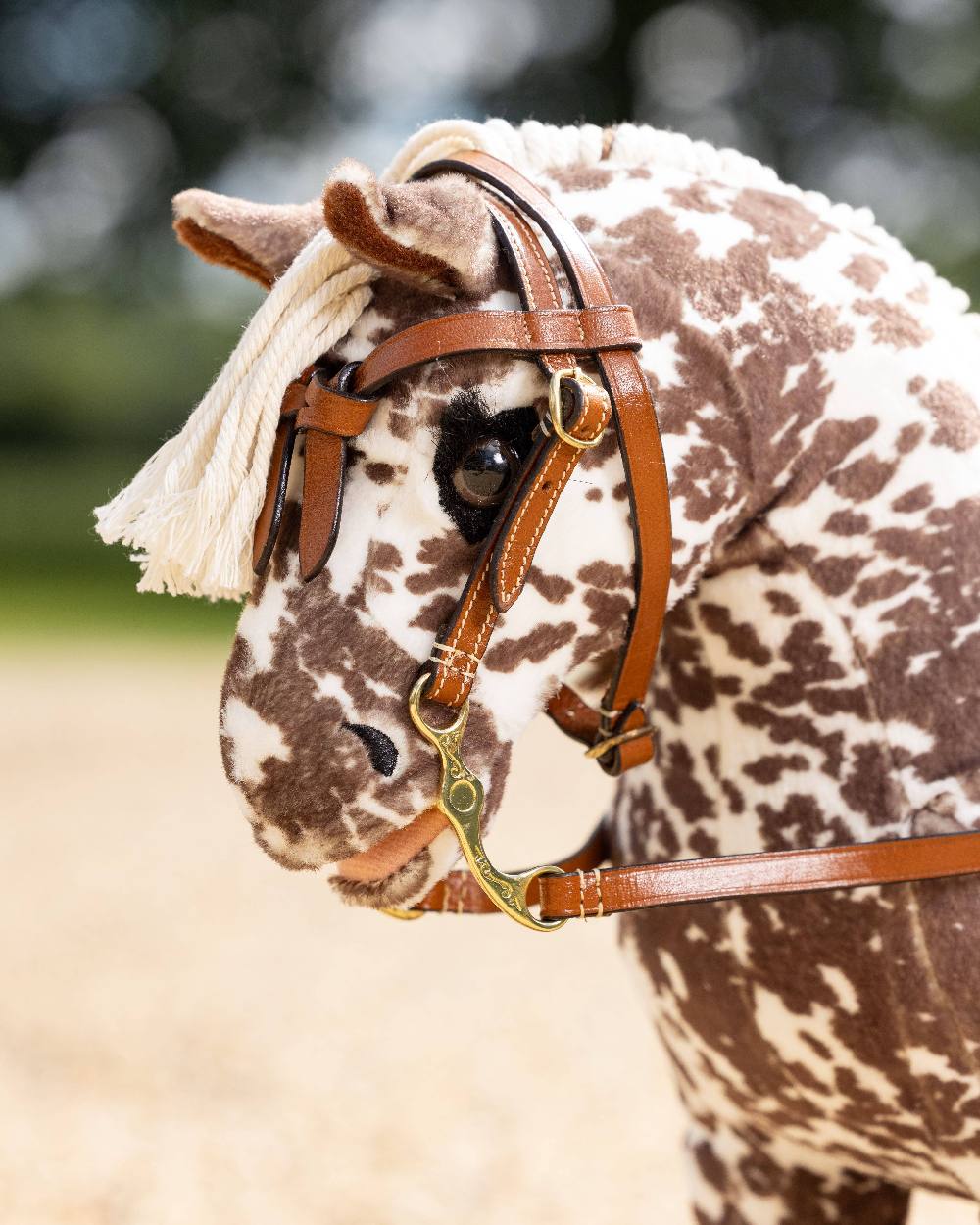 Tan coloured LeMieux Toy Pony Western Bridle on blurry background 