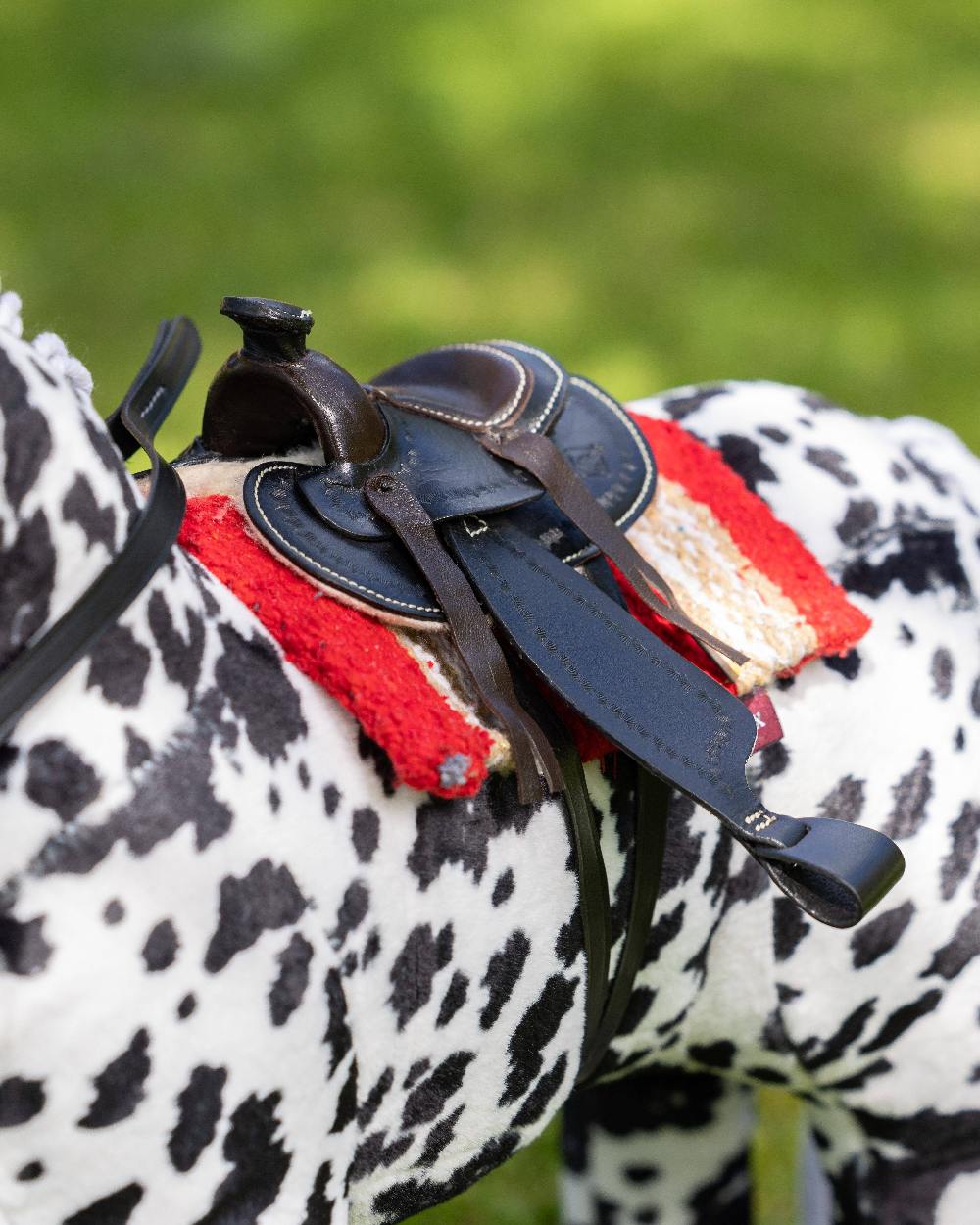 Black coloured LeMieux Toy Pony Western Saddle on blurry green background 