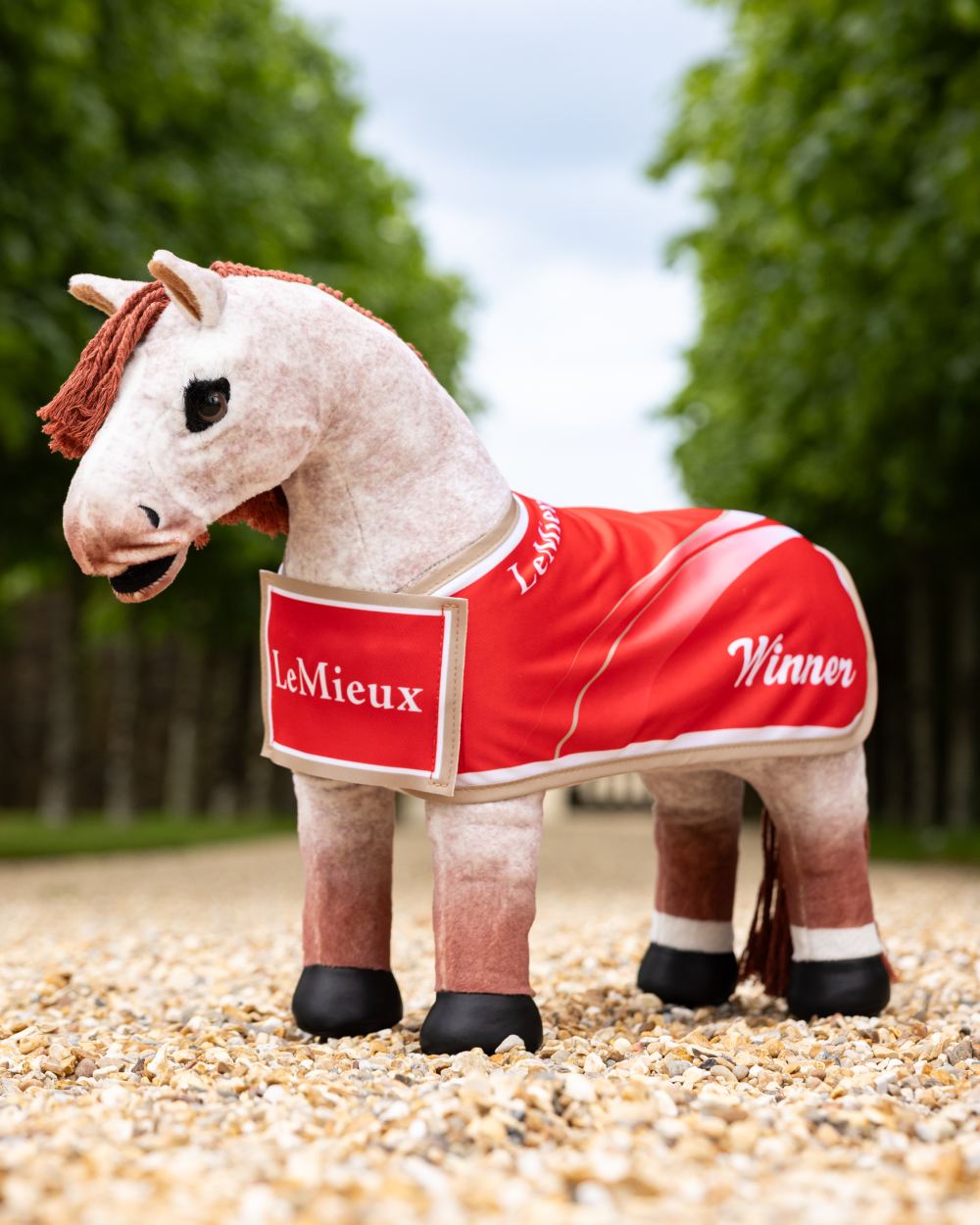 Red coloured LeMieux Toy Pony Winners Rug on tree background 