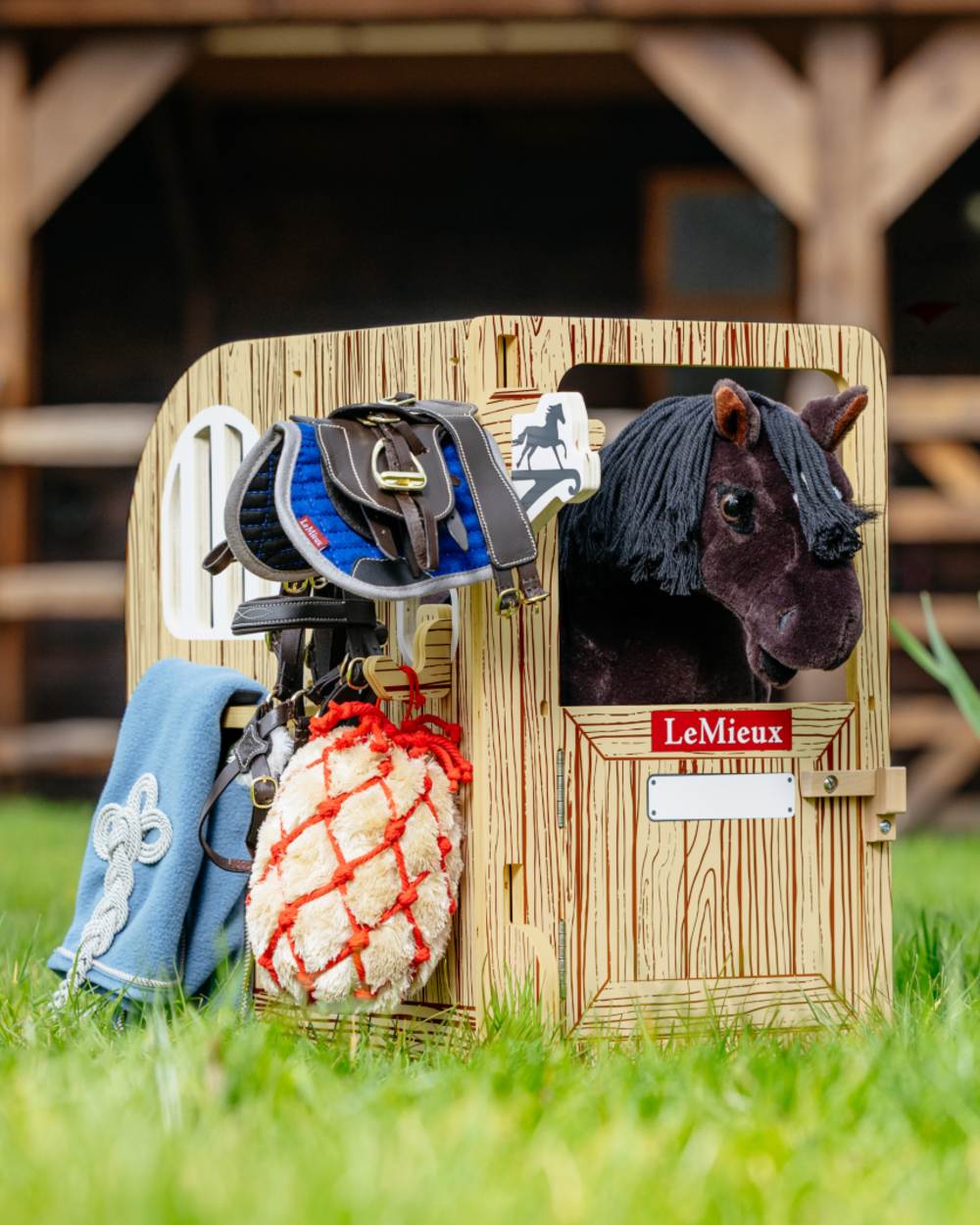 Wooden coloured LeMieux Toy Pony Wooden Stable Set on grass background 