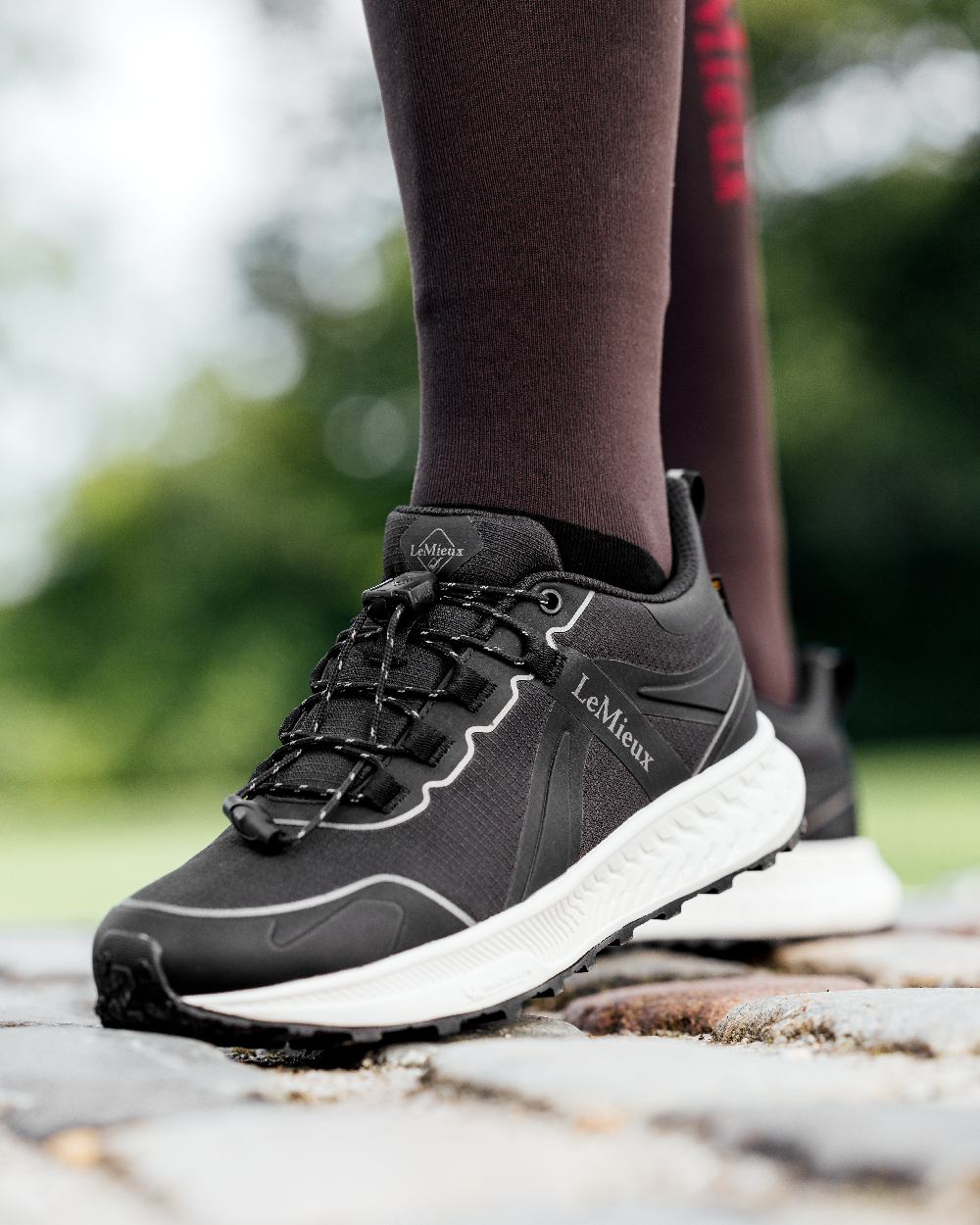 Black coloured LeMieux Trax Sports Waterproof Trainers on blurry background 