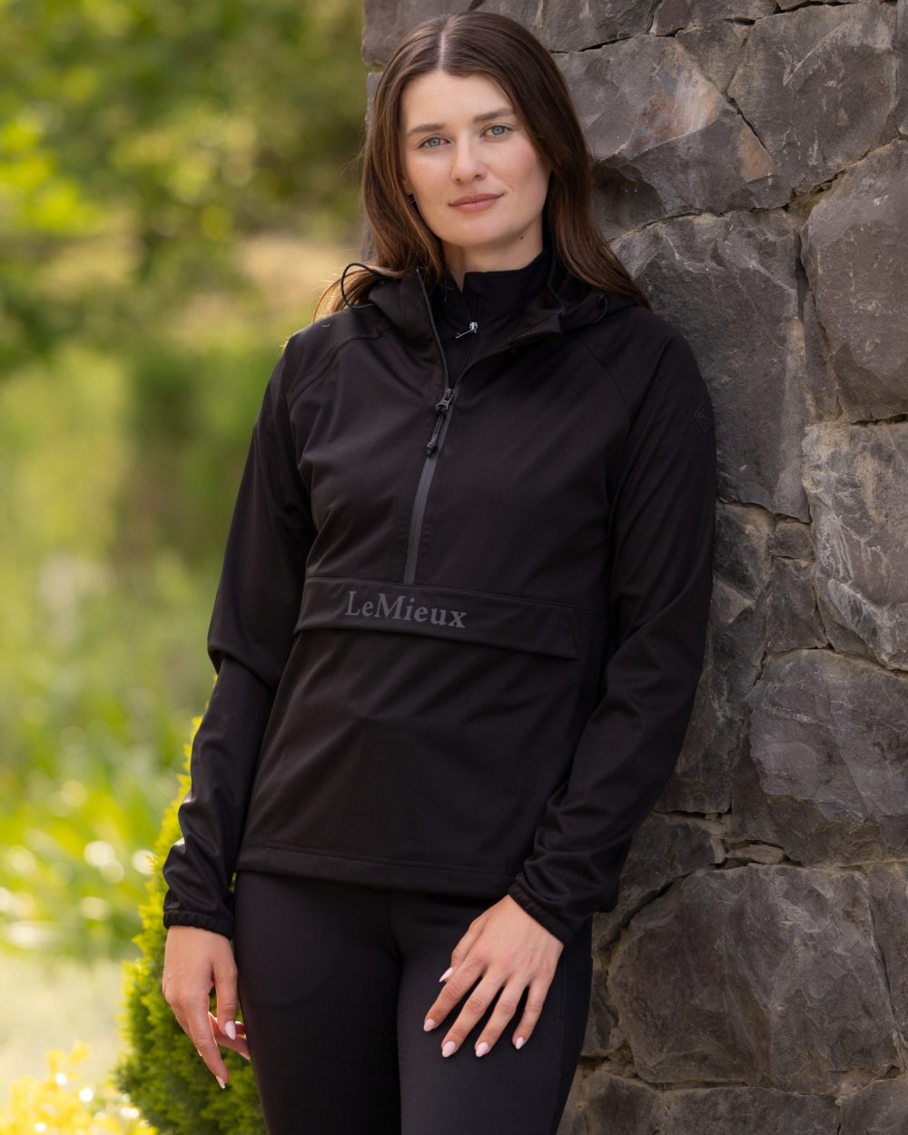 Black coloured LeMieux Womens Perri Half Zip Waterproof Jacket on tree background 